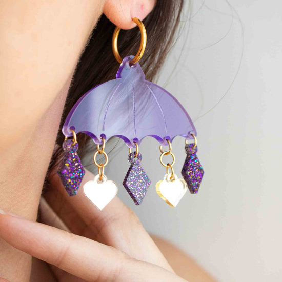 Boucles d oreilles violettes en acrylique découpe laser, bijou colore artisanal Limonade Studio, portée sur modèles, pampilles en mouvement et montré sur packaging.